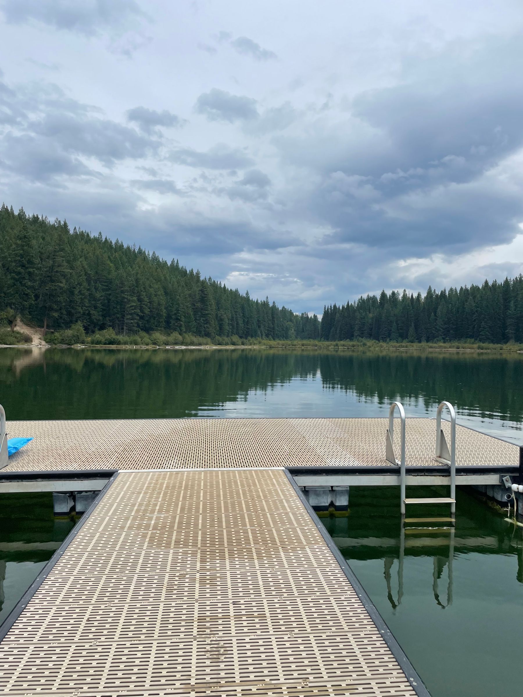 A wooden dock on a calm lake surrounded by forest